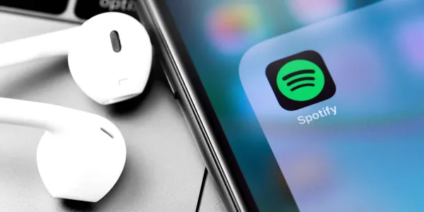 Apple AirPods sitting next to Spotify app logo